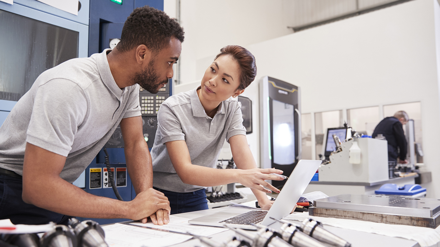 Two Engineers Using CAD Programming Software On Laptop