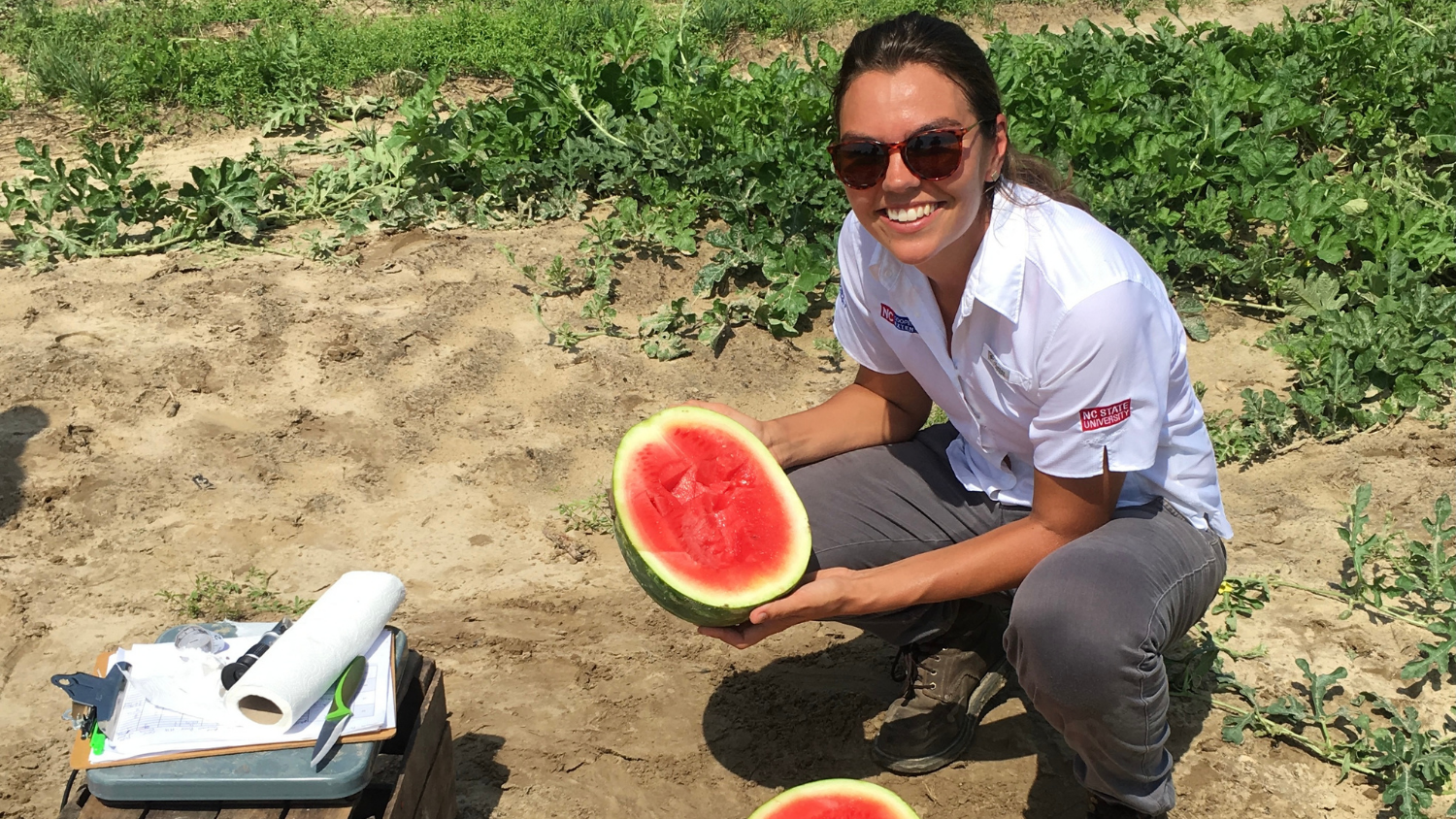 Nettie Baugher holds a watermelon in the field.