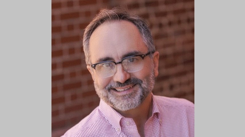 Dan Harris headshot in front of brick wall.