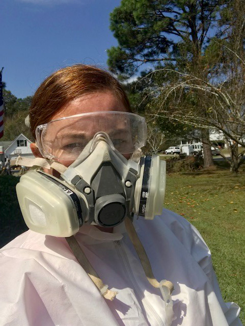 Brandy Osborne looks at the camera, wearing a Tyvek suit and a respirator mask.