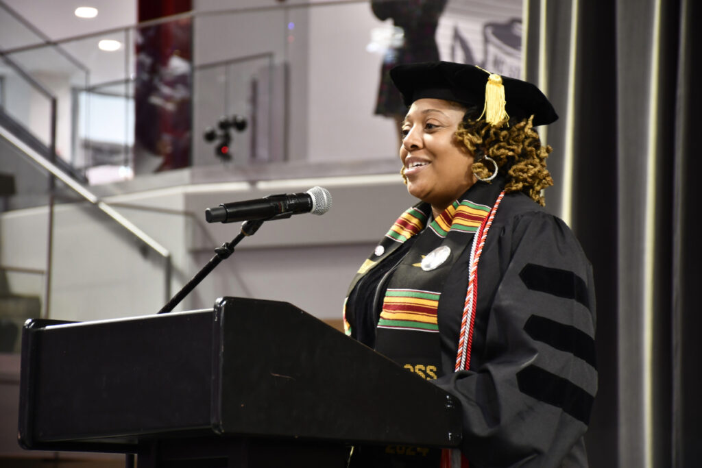 Cherrelle in graduation regalia standing at a lecturn