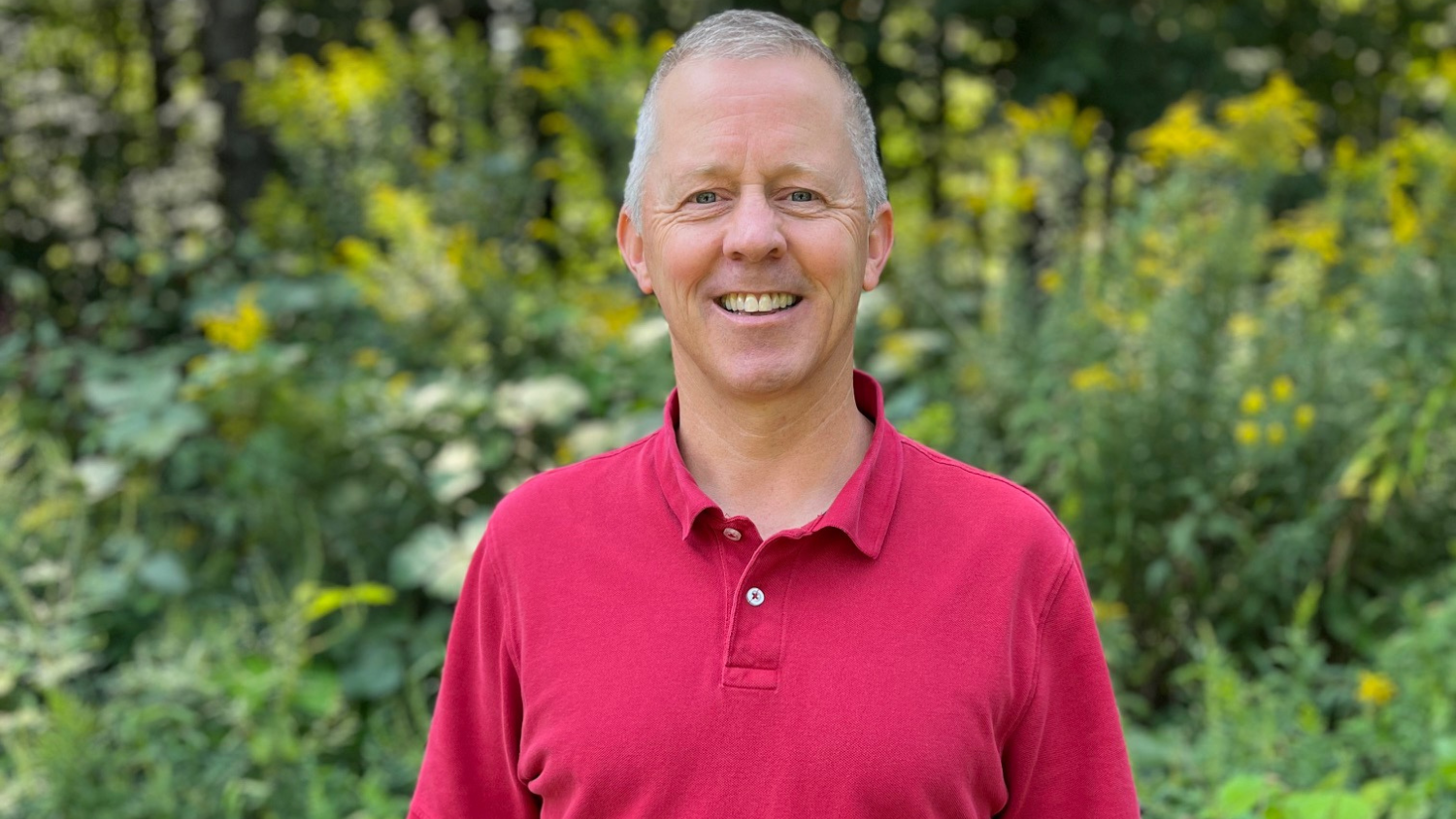 George Ivey smiling outside in front of greenery.